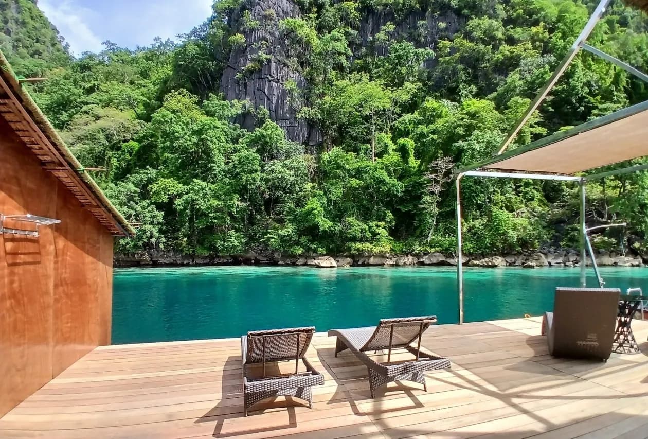 Deck overlooking turquoise lagoon water at sunset with limestone cliffs